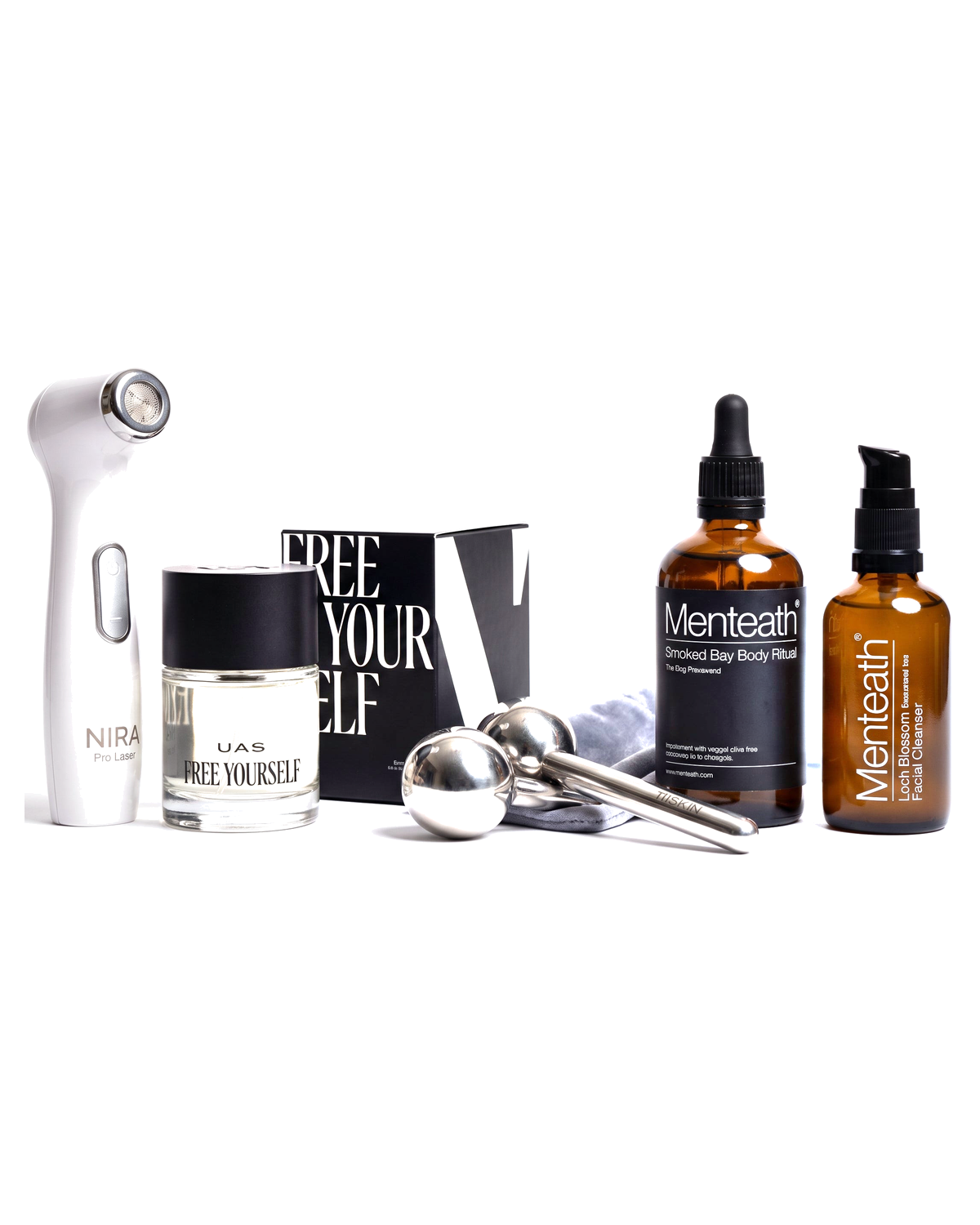 The Premium Beauty Ritual kit - NIRA Pro Laser device, UAS Free Yourself perfume, Menteath body ritual and facial cleanser, and steel facial rollers, on a white background